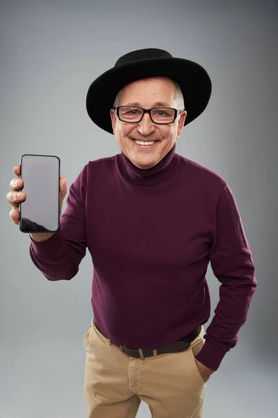 Ευτυχισμένος άνθρωπος σε μαύρο καπέλο που δείχνει η οθόνη του σύγχρονου gadget — Φωτογραφία Αρχείου