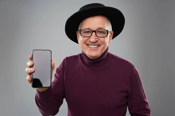 Hombre maduro confiado sonriendo mientras está de pie con un teléfono inteligente moderno — Foto de Stock