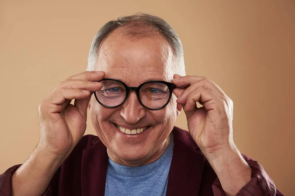 Mature man feeling confident while putting on his glasses — Stock Photo, Image