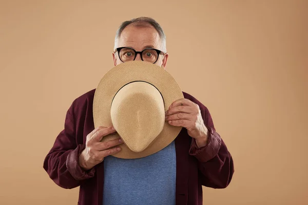 Взрослый мужчина в очках и с соломенной шляпой в руках — стоковое фото