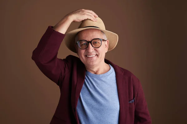 Hombre feliz en sombrero de paja poniendo una mano en él y sonriendo — Foto de Stock