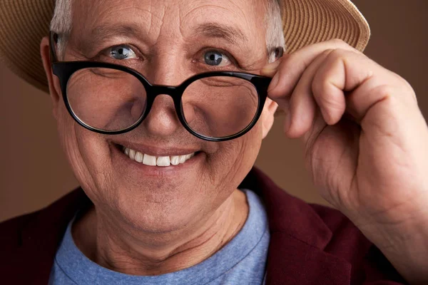 Hombre positivo con gafas y sonriendo mientras los toca — Foto de Stock