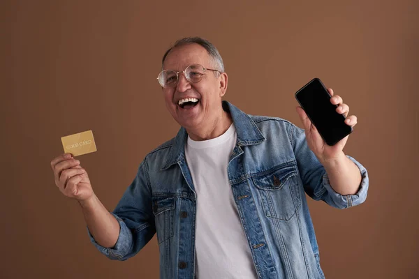 Glada vuxna skrattar samtidigt visar sin smartphone och guld kort — Stockfoto