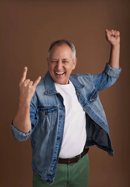 Excited adult man making devil horns gesture and smiling