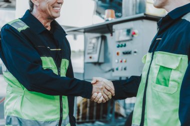 Gülümseyen adam tokalaşırken meslektaşı ile işyerinde