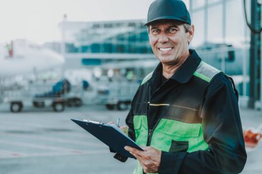 Tecrübeli adam siyah klasör havaalanında tutan gülümseyerek