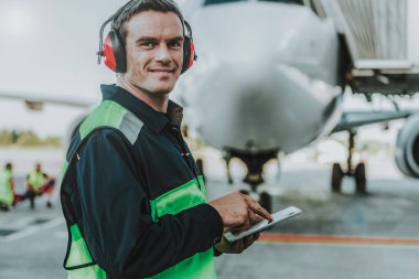 Büyük uçak önünde duran gülümseyen yakışıklı işçi