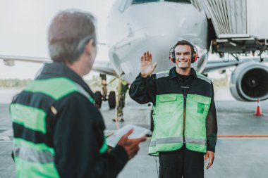 Kırmızı kulaklık mekanik el sallayarak yakışıklı çalışan gülümseyen