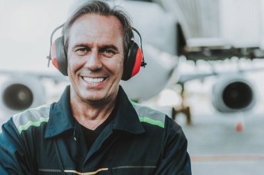 Büyük uçak önünde yakışıklı mekanik ayakta gülümseyen