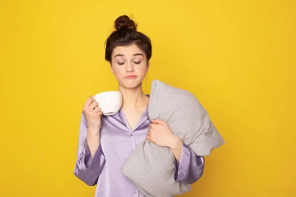 Сонная девушка с чашкой кофе и подушкой — стоковое фото