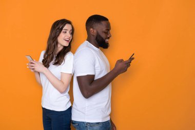 Beyaz tişörtler içinde yarım uzunlukta ırklar arası çift kollarında akıllı telefonlar tutan