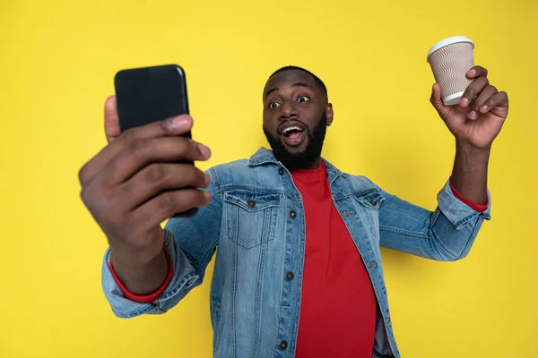 Taille up van grappige Afrikaanse man houden beker en smartphone in armen — Stockfoto