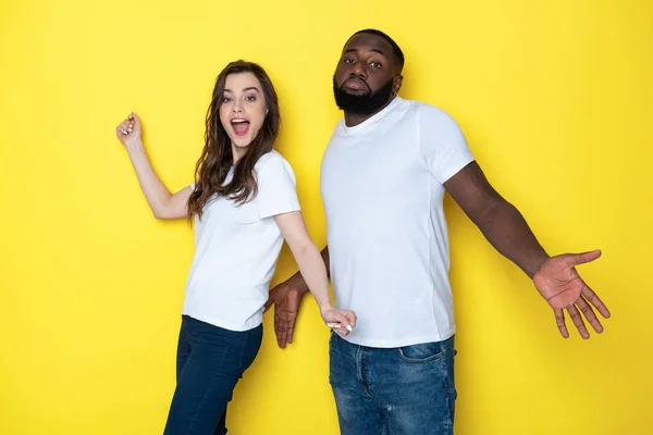 Молода міжрасова пара в білих футболках позує за камеру в студії — стокове фото
