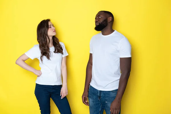 Нещаслива міжрасова пара в білих футболках позує за камеру в студії — стокове фото