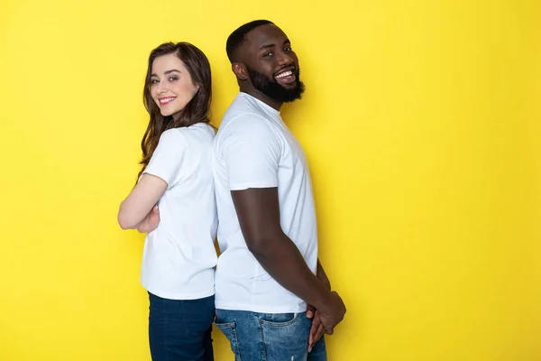 Усміхнена міжрасова пара в білих футболках позує за камеру в студії — стокове фото