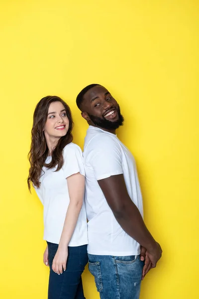 Щаслива міжрасова пара в білих футболках позує за камеру в студії — стокове фото