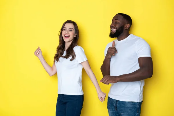 Felice coppia interrazziale in bianco T-shirt in posa per la fotocamera in studio — Foto Stock