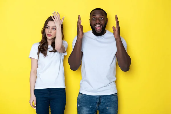 Jeune couple interracial en blanc T-shirts posant pour caméra en studio — Photo