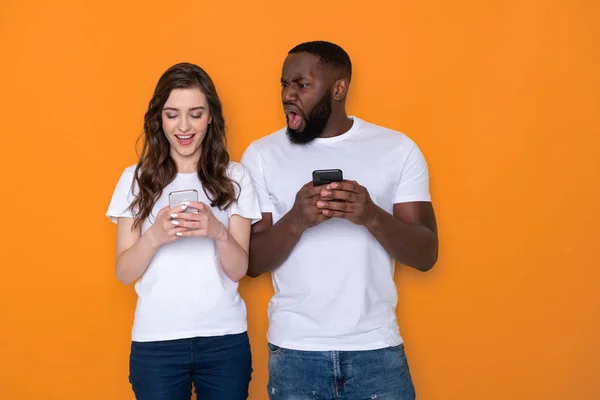 Tour de taille de couple interracial en T-shirts blancs tenant des smartphones dans les bras — Photo