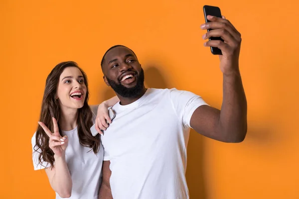 Demi-longueur de couple interracial en T-shirts blancs tenant les smartphones dans les bras — Photo