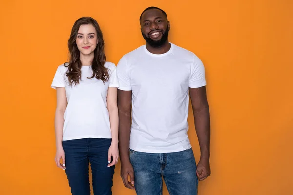 Красива міжрасова пара в білих футболках позує на камеру — стокове фото