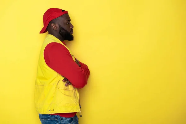 Vista lateral del hombre africano barbudo con las manos cruzadas sobre fondo amarillo — Foto de Stock