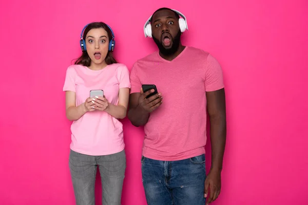 Foto recortada de una pareja interracial sorprendida con auriculares modernos en el estudio — Foto de Stock