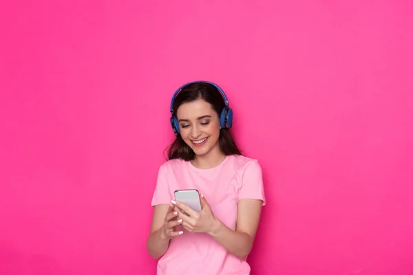 Cintura arriba de morena alegre chica caucásica con auriculares sobre fondo rosa — Foto de Stock