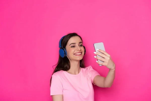 Cintura arriba de morena alegre chica caucásica con auriculares sobre fondo rosa — Foto de Stock