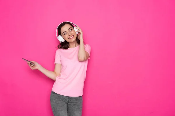 Foto recortada de una chica morena sonriente con auriculares y escuchando música — Foto de Stock