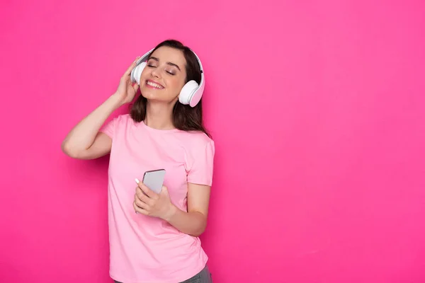 Foto recortada de menina branca sorridente com olhos fechados ouvindo música — Fotografia de Stock