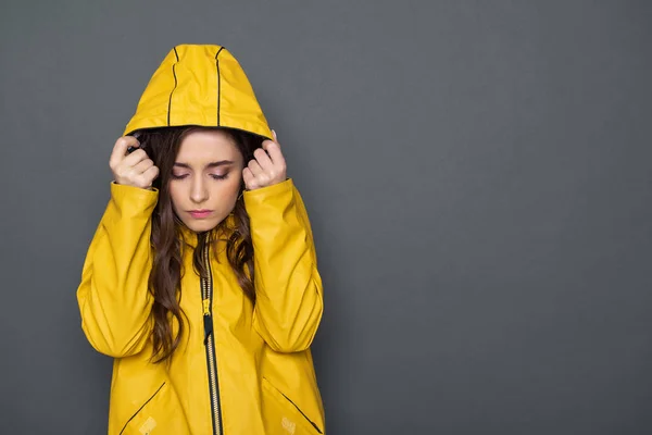 Tour de taille de triste fille caucasienne vêtue d'imperméable jaune en studio — Photo