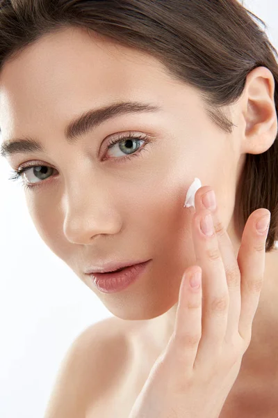 Tender young female applying cream on cheek — Stock Photo, Image