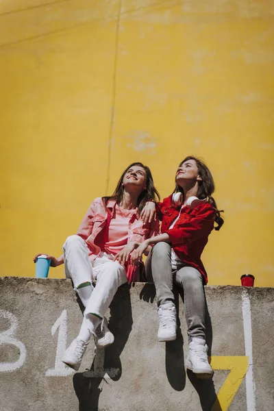 Dos chicas felices sentadas juntas en el parapeto —  Fotos de Stock
