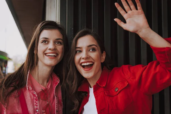 İki mutlu hipster kız birine el sallıyor — Stok fotoğraf