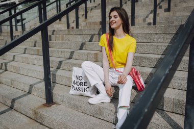 Merdivenlerde oturan oldukça gülümseyen hipster kız