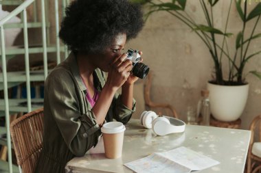 Kıvırcık saçlı Afrikalı kadının kafeteryada fotoğraf çekmesiyle yüksek açı