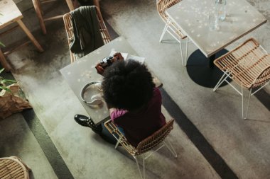 Kıvırcık saçlı meşgul Afrikalı kadın kafeteryada fotoğraf çekiyor