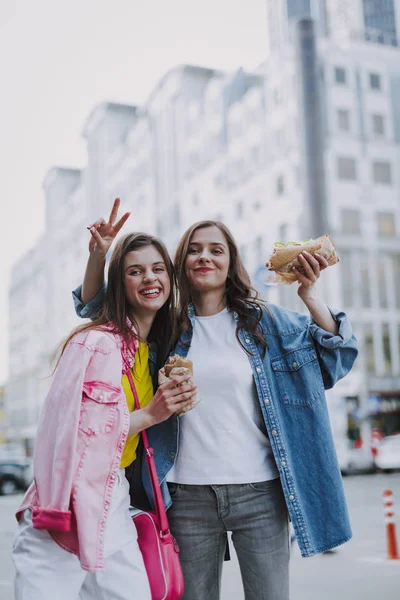 Hembras felices haciendo foto divertida con perros calientes —  Fotos de Stock