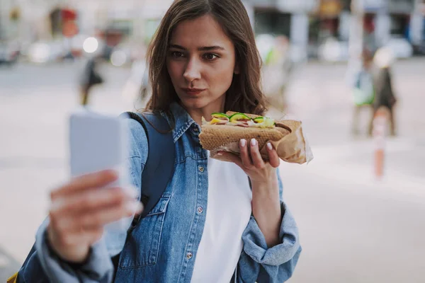 Jolie femelle faisant selfie drôle avec hot dog — Photo