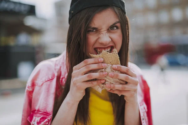 Bastante chica hipster hambrienta comiendo hot dog — Foto de Stock