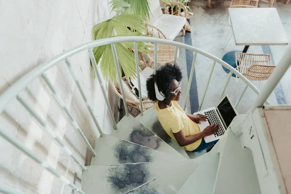 Seitenansicht einer Afrikanerin, die an digitalen Geräten in Innenräumen arbeitet — Stockfoto