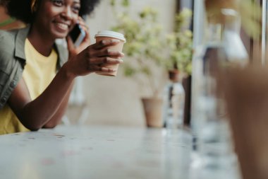 Kafede kahve içen mutlu Afrikalı bayan Düşük açı