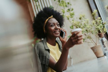 Kafede kahve içen mutlu Afrikalı bayan Düşük açı