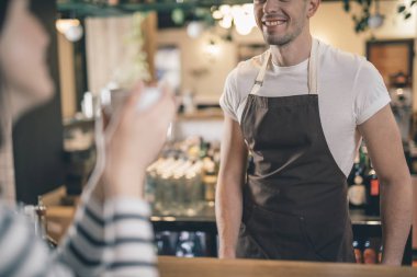 Bar tezgahında gülümseyen erkek barista yakın