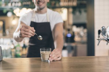 Gülümseyen barista kakao bardağının yanında kaşık tutuyor