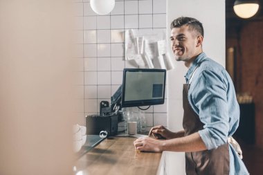 Bar tezgahının önünde dururken gülümseyen neşeli barista