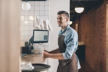 Bar tezgahının önünde gülümseyen genç garson