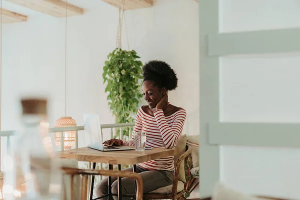 Halbe Länge der glücklichen Afrikanerin, die im Café am Laptop arbeitet — Stockfoto