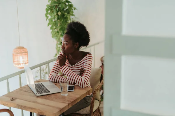 Halbe Länge einer ruhigen Afrikanerin, die an einem Tisch im Café sitzt — Stockfoto